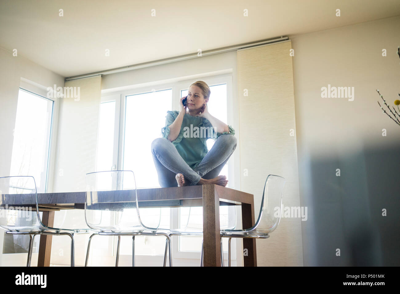 Geschäftsfrau am Telefon sitzen barfuß auf Tisch Stockfoto