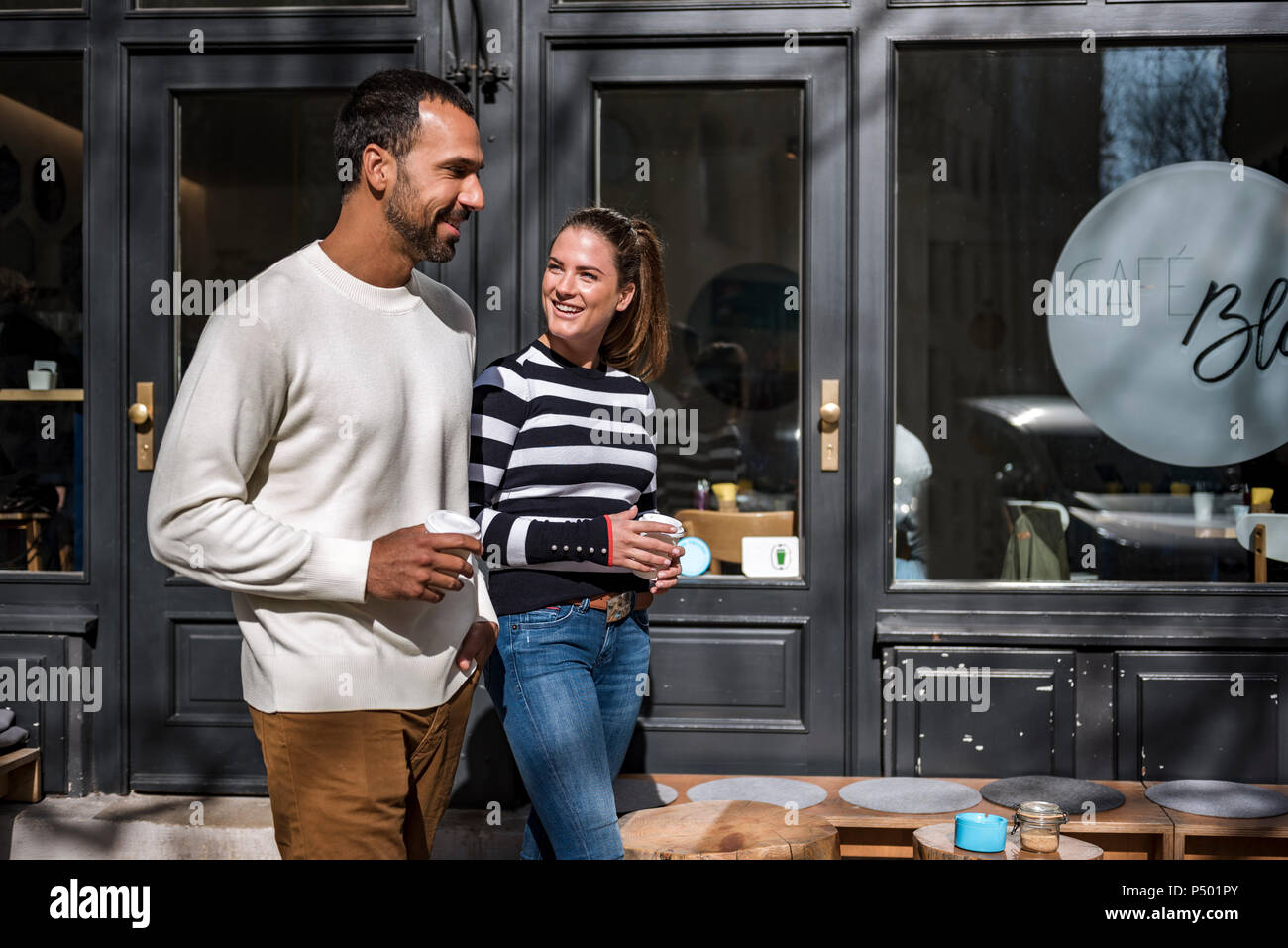 Mann und Frau mit Takeaway cups zu Fuß außerhalb eines Cafe Stockfoto