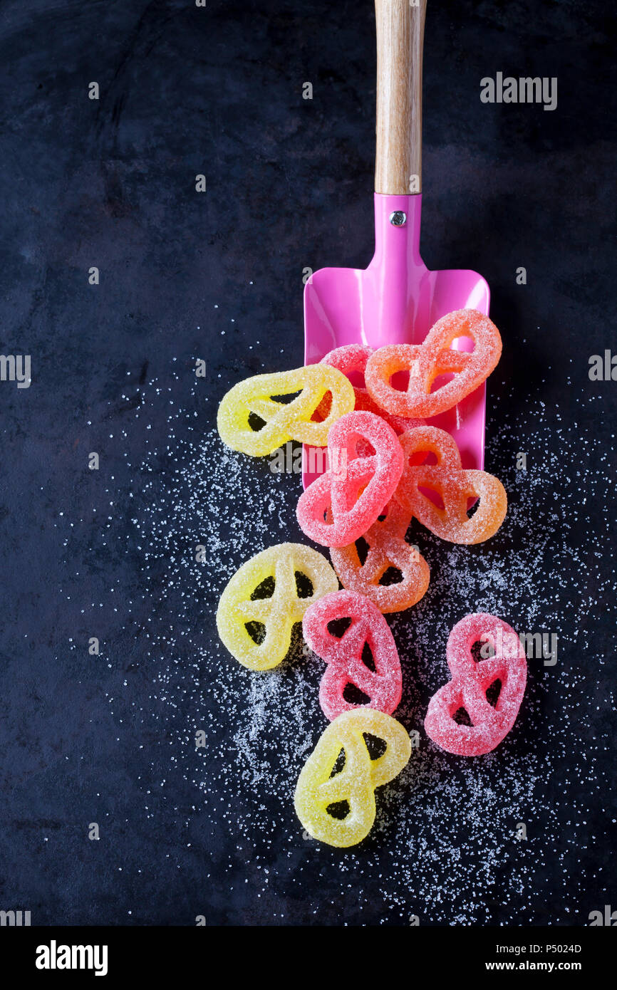 Zucker, Brezeln und pink Schaufel auf dunklem Boden Stockfoto