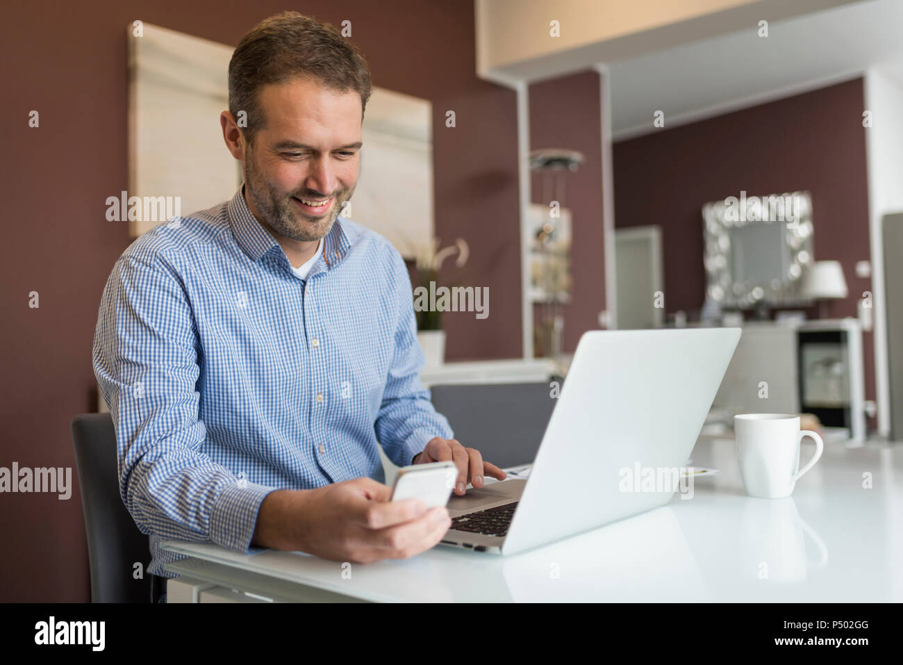 Mann an Schreibtisch sitzen, mit Laptop Stockfoto