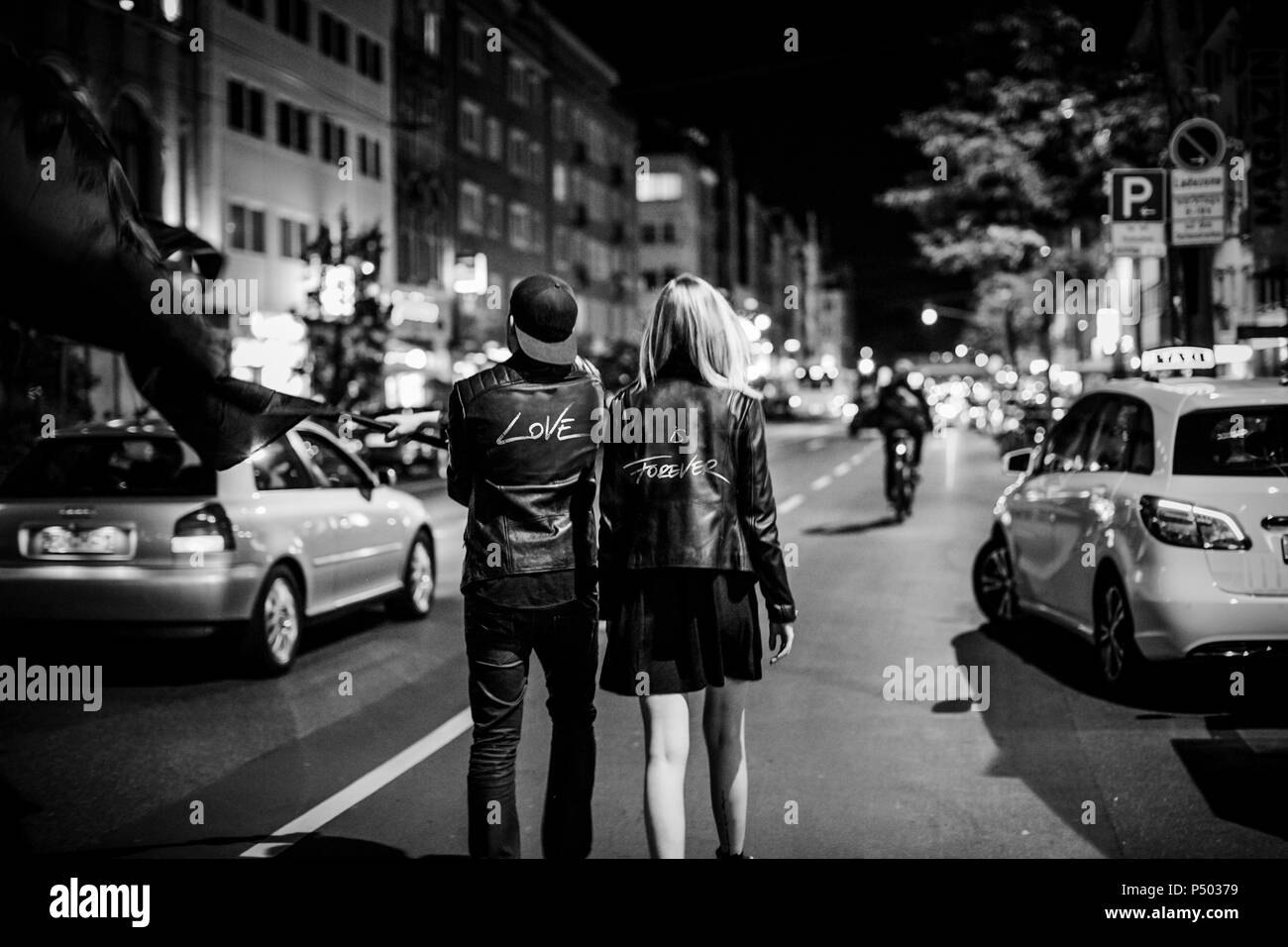 Rückansicht des jungen Paares mit Black Flag zu Fuß auf der Straße bei Nacht Stockfoto