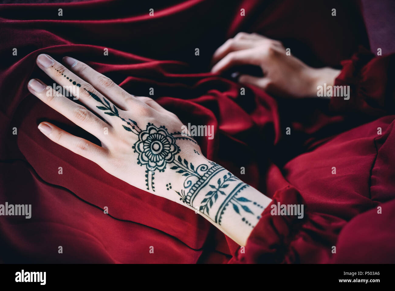 Woman's Hand mit Henna Tätowierung auf rotem Tuch Stockfoto