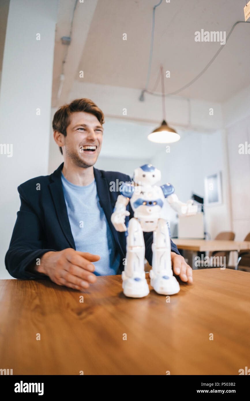 Laughing Man mit Roboter auf Tisch Stockfoto