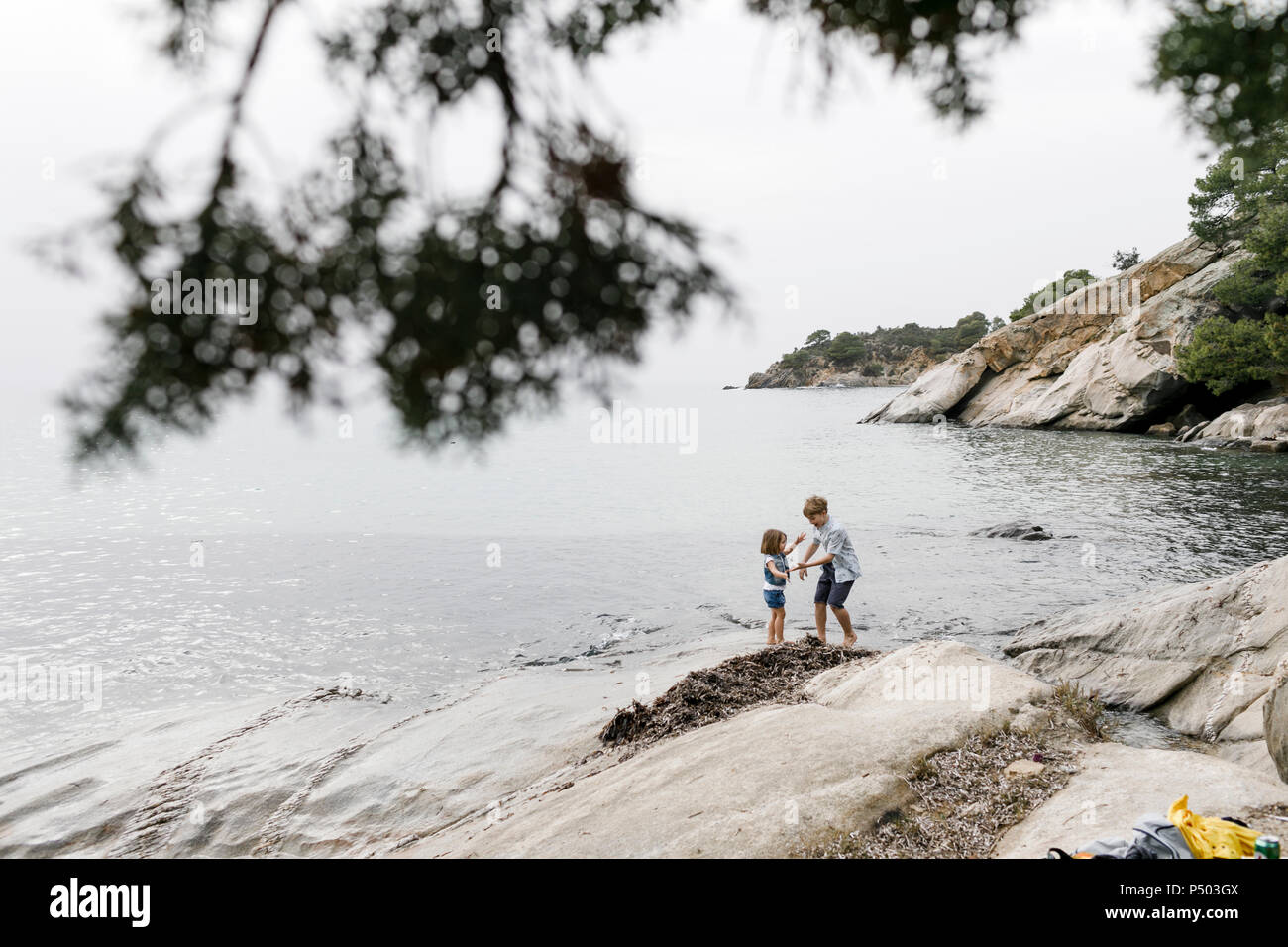 Griechenland, Chalkidiki, Bruder und kleine Schwester spielen zusammen am Strand Stockfoto