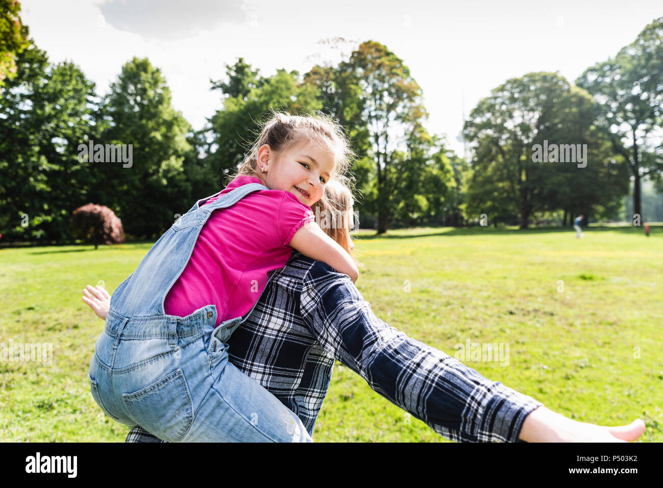 Glücklich auf dem Rücken der Mutter in einem Park Stockfoto