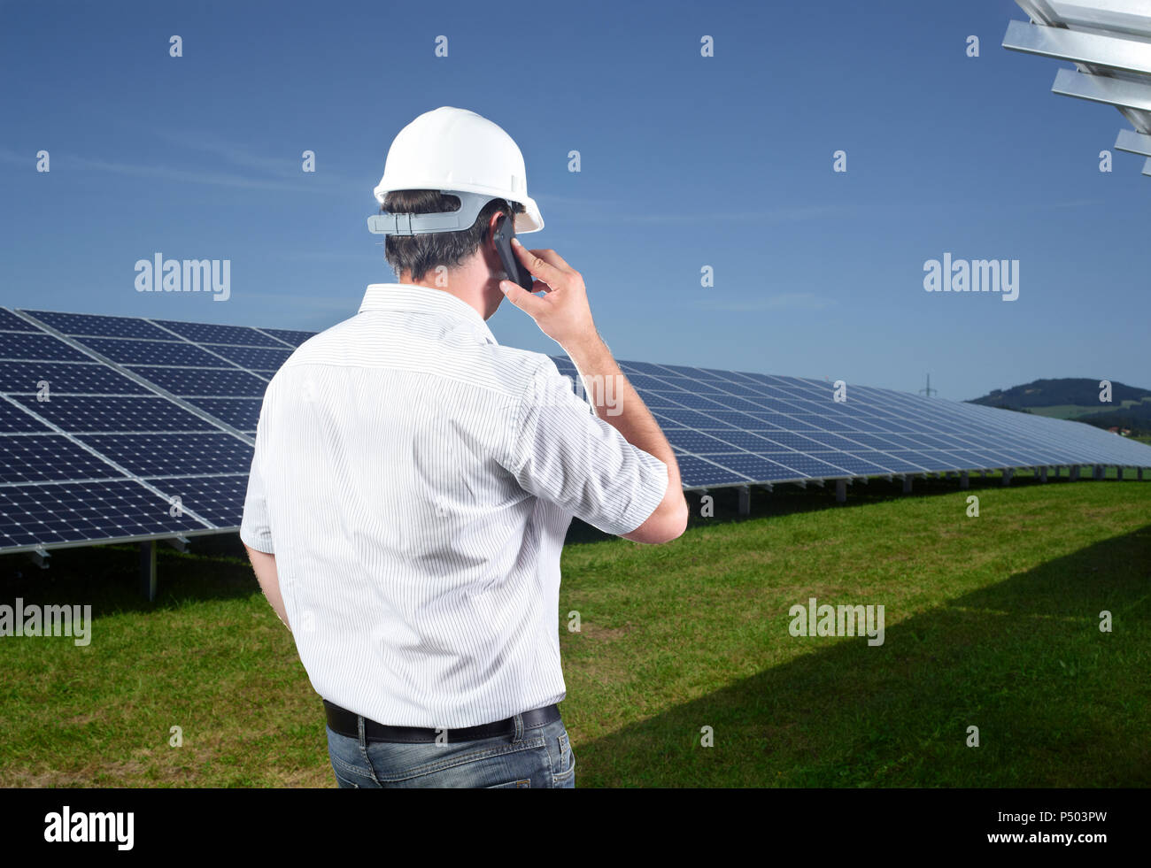 Rückansicht der Techniker am Telefon vor der Solaranlage Stockfoto