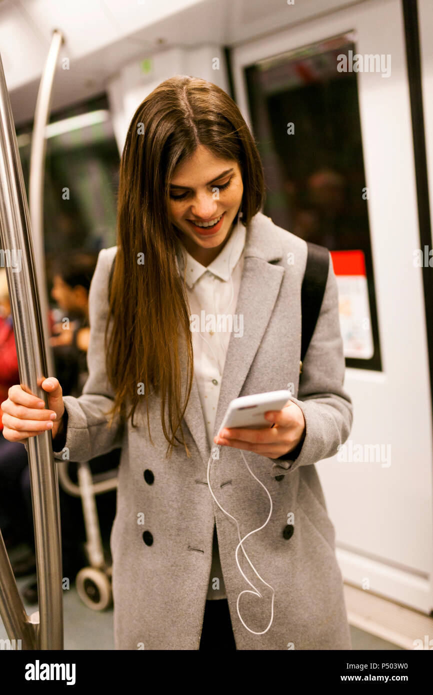 Junge Geschäftsfrau mit Handy in der U-Bahn Stockfoto