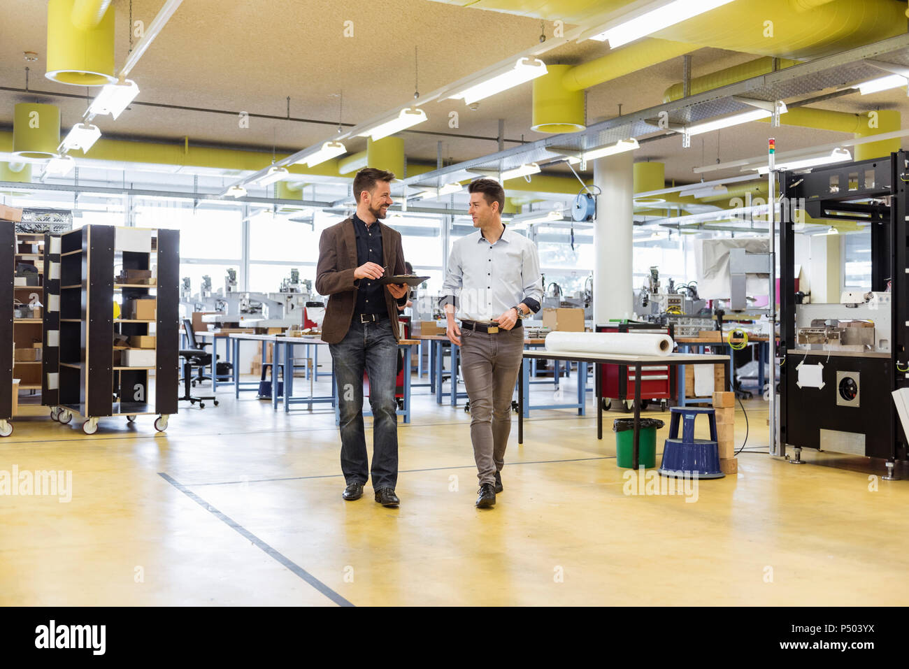 Zwei Männer laufen und sprechen in der Factory Stockfoto