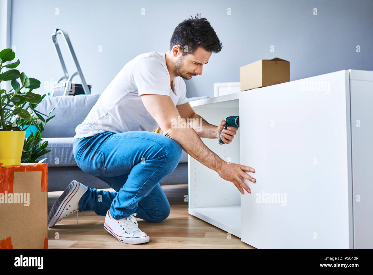 Mann Montage ein Bücherregal in neue Wohnung Stockfoto