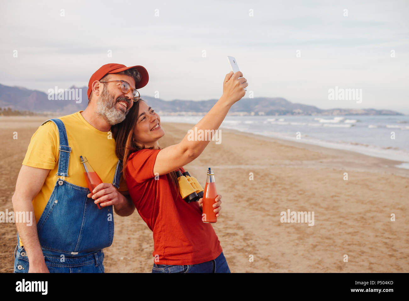 Paar mit alkoholfreien Getränken unter selfie mit Smartphone am Strand Stockfoto