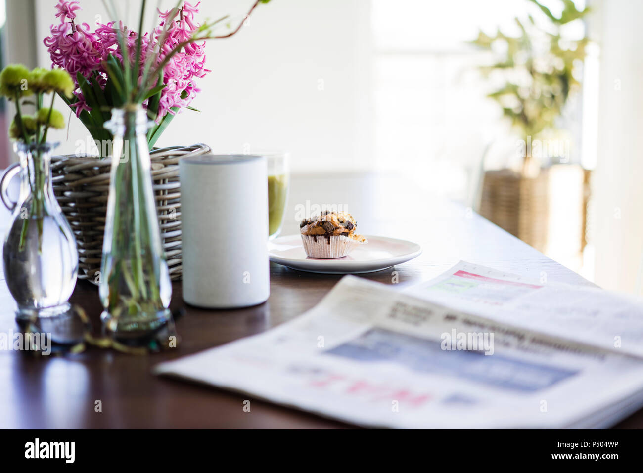 Zeitung, Blumenvasen, Lautsprecher und Muffin auf Tisch Stockfoto