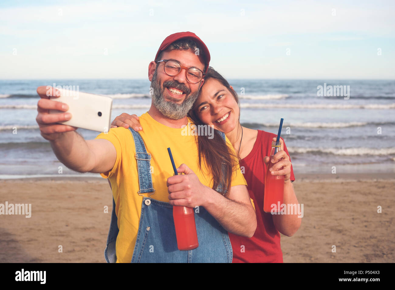 Paar mit alkoholfreien Getränken unter selfie mit Smartphone am Strand Stockfoto