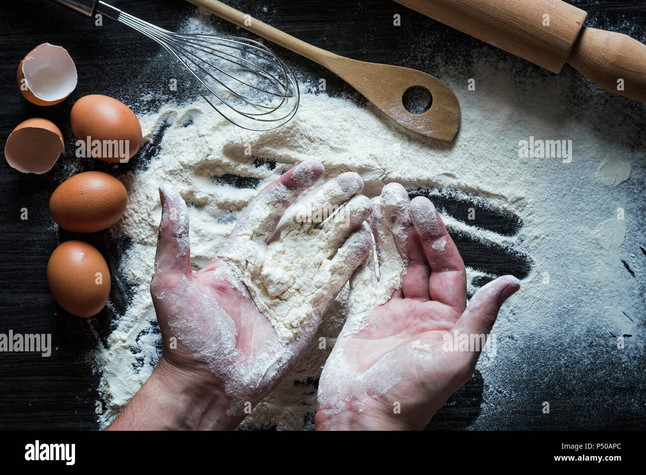 Erwachsene mann Hände Arbeit mit Mehl. Hintergrund mit einem Nudelholz, Mehl und rohe Eier Stockfoto