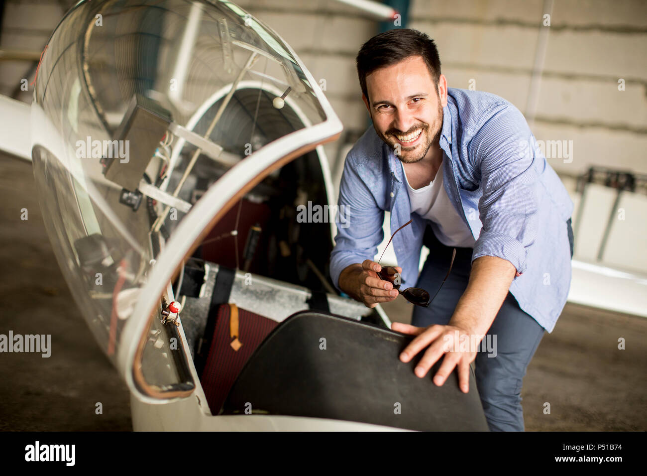 Hübscher junger Pilot Kontrolle Flugzeug im Hangar Stockfoto