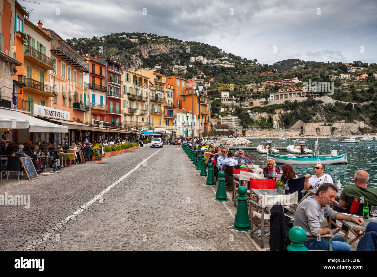 Bunte Häuser und Menschen an Outdoor Cafe Restaurant in Villefranche-sur-Mer Ferienort am Mittelmeer auf dem französischen Riviera, Frankreich, Alpes Mariti Stockfoto