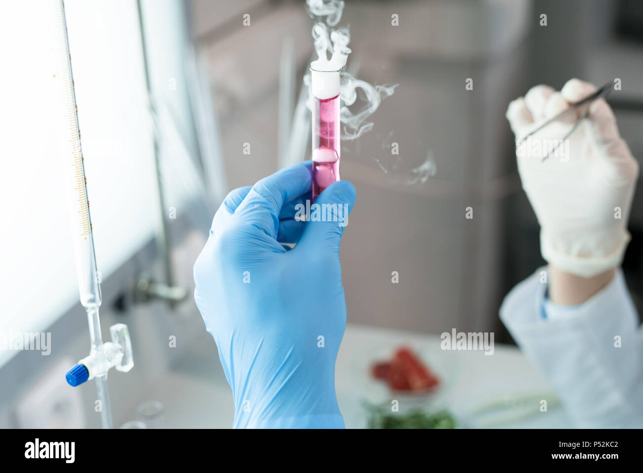 Wissenschaftler halten Rauchen rosa Reagenzglas Stockfoto