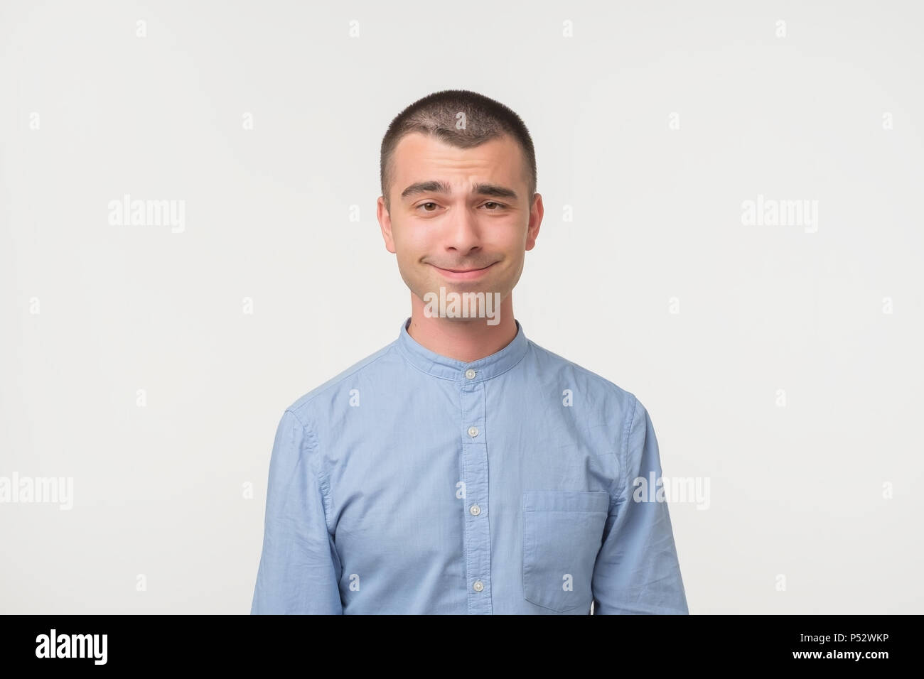 Stattliche Latino Mann zeigt überrascht Lächeln grimasse oder Mimik, auf weißem Hintergrund. Die lustige Emotion auf dem Gesicht Stockfoto