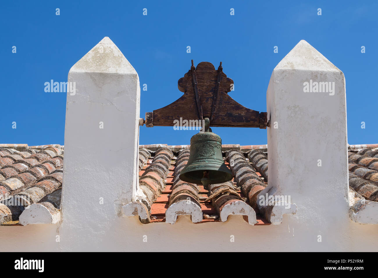 Dach einer alten Kirche Nossa Senhora da Rocha in Porches, Algarve, Portugal. Orange alte Dachziegel. Glockenturm mit einer Glocke. Strahlend blauen Himmel im Hinterg Stockfoto