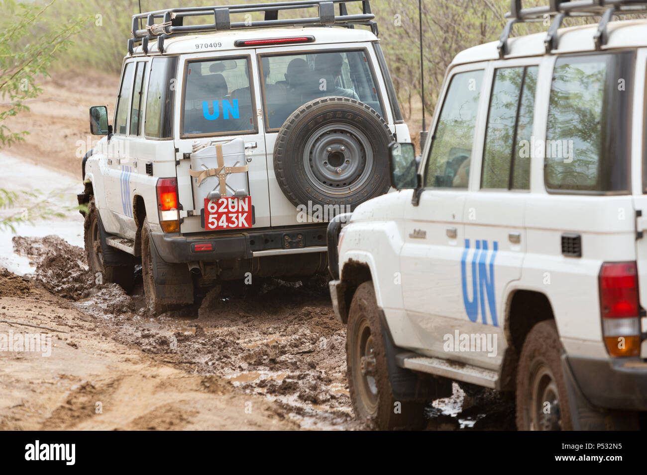 KAKUMA, Kenia - Zwei UN-Land Rover fahren auf einer verregneten Landstraße. Stockfoto