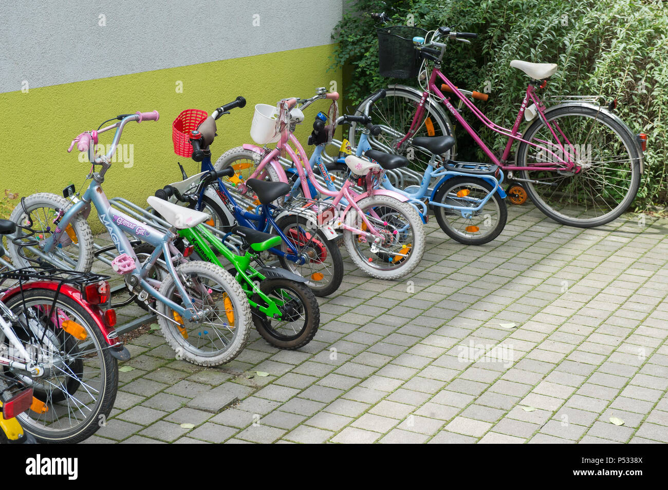 Verschiedene Größen von Fahrrädern vor einer Kindertagesstätte Stockfoto