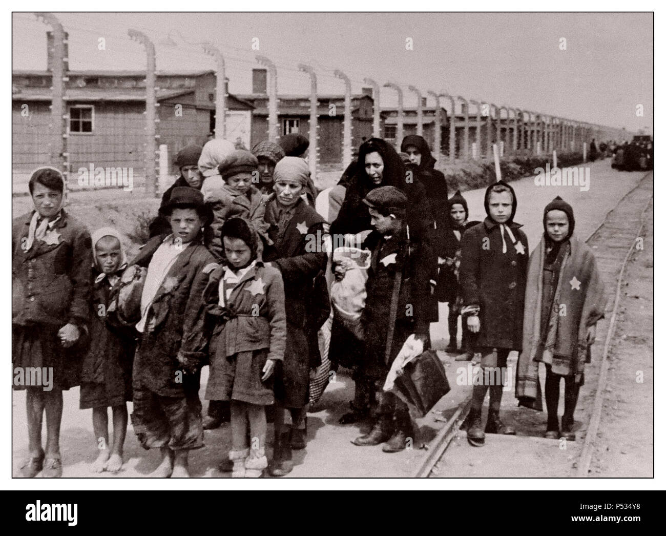 Jüdische Kinder in AUSCHWITZ, die von den Nazis ausgewiesene gelbe Sterne tragen, kommen in Auschwitz-Birkenau an. Ein Konzentrations- und Vernichtungslager der deutschen Nazis im 2. Weltkrieg. Jüdische Kinder ließen die größte Gruppe ins Lager deportieren. Sie wurden in der Regel zusammen mit Erwachsenen dorthin geschickt, beginnend Anfang 1942, als Teil der „endgültigen Lösung der jüdischen Frage“ – der totalen Zerstörung der jüdischen Bevölkerung Europas… Auschwitz war ein Netzwerk von deutschen Konzentrations- und Vernichtungslagern, die vom Dritten Reich in polnischen Gebieten errichtet und betrieben wurden, die während des Zweiten Weltkriegs von Nazi-Deutschland annektiert wurden Stockfoto