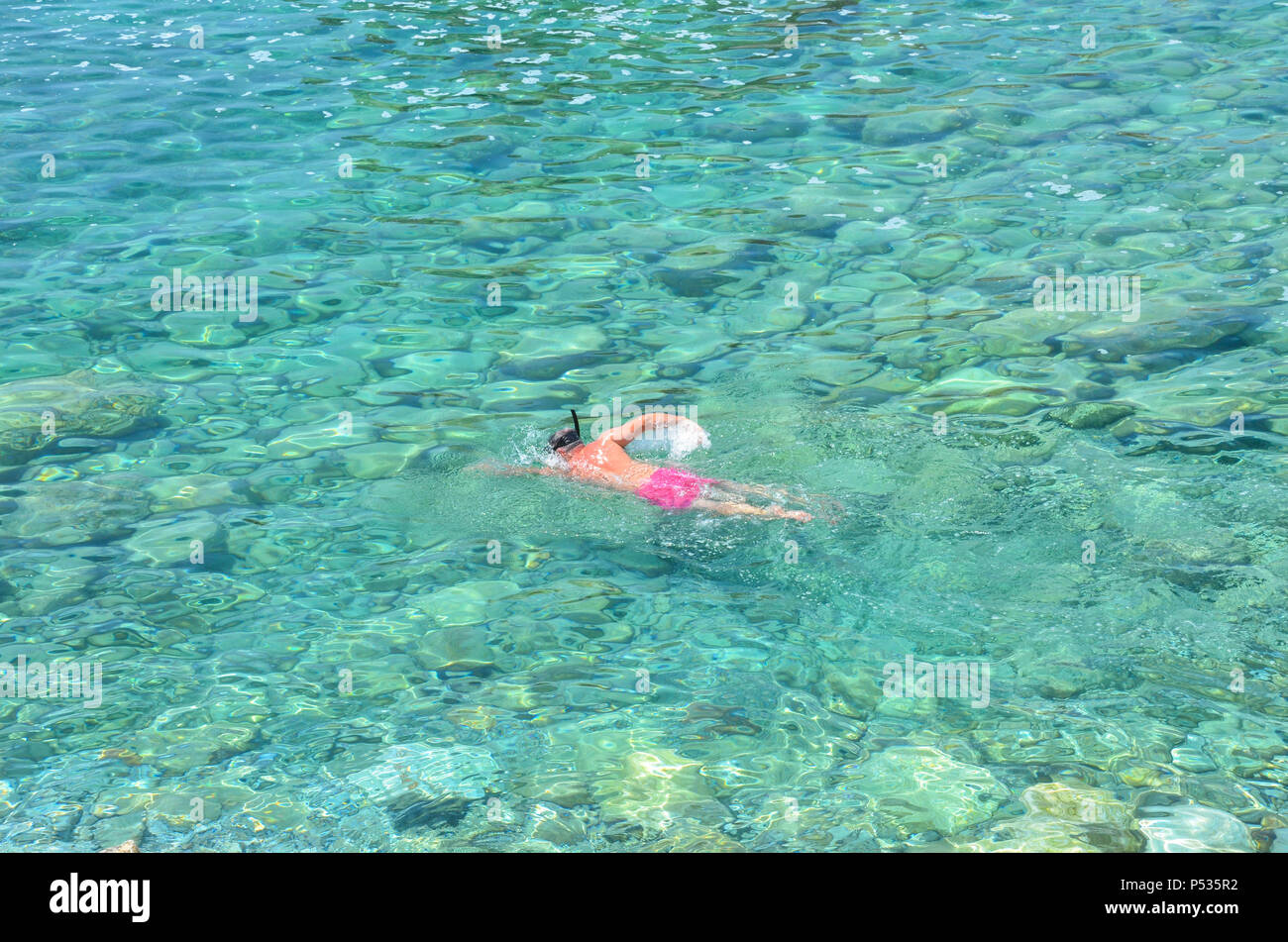 Ein Mann Schwimmen in der Nähe von Sveti Nikola Insel (bekannt als 'Hawaii' oder 'Školj'), Budva, Montenegro, Adria, Balkan, Mai 2018 Stockfoto