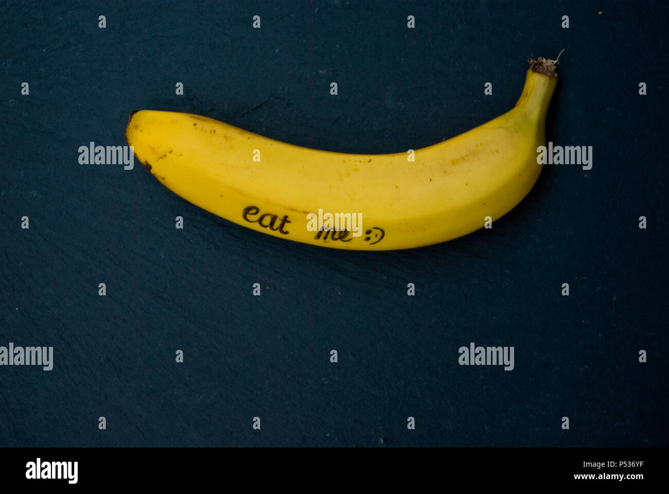 Single reife, gelbe Banane Verlegung auf schwarzen Hintergrund mit Schreiben ' mich essen' und Leerzeichen kopieren Stockfoto