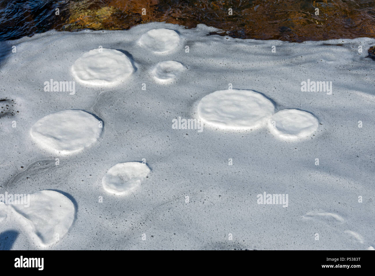 Gefrorene Schaum Pfannkuchen in die Kreise durch gedreht werden, während in einem Eddy im Fluss Coupall, Glencoe, Hochland, Schottland, UK erodiert Stockfoto