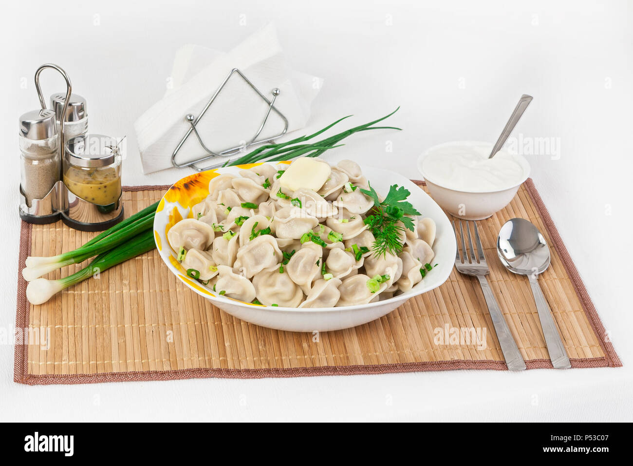 Russische Knödel mit Kräutern und Zwiebeln. Ravioli mit Fleisch. Das Gericht ist in einem Teller serviert. Serviert mit Knödel ist Sauerrahm in eine Schüssel geben. Stockfoto