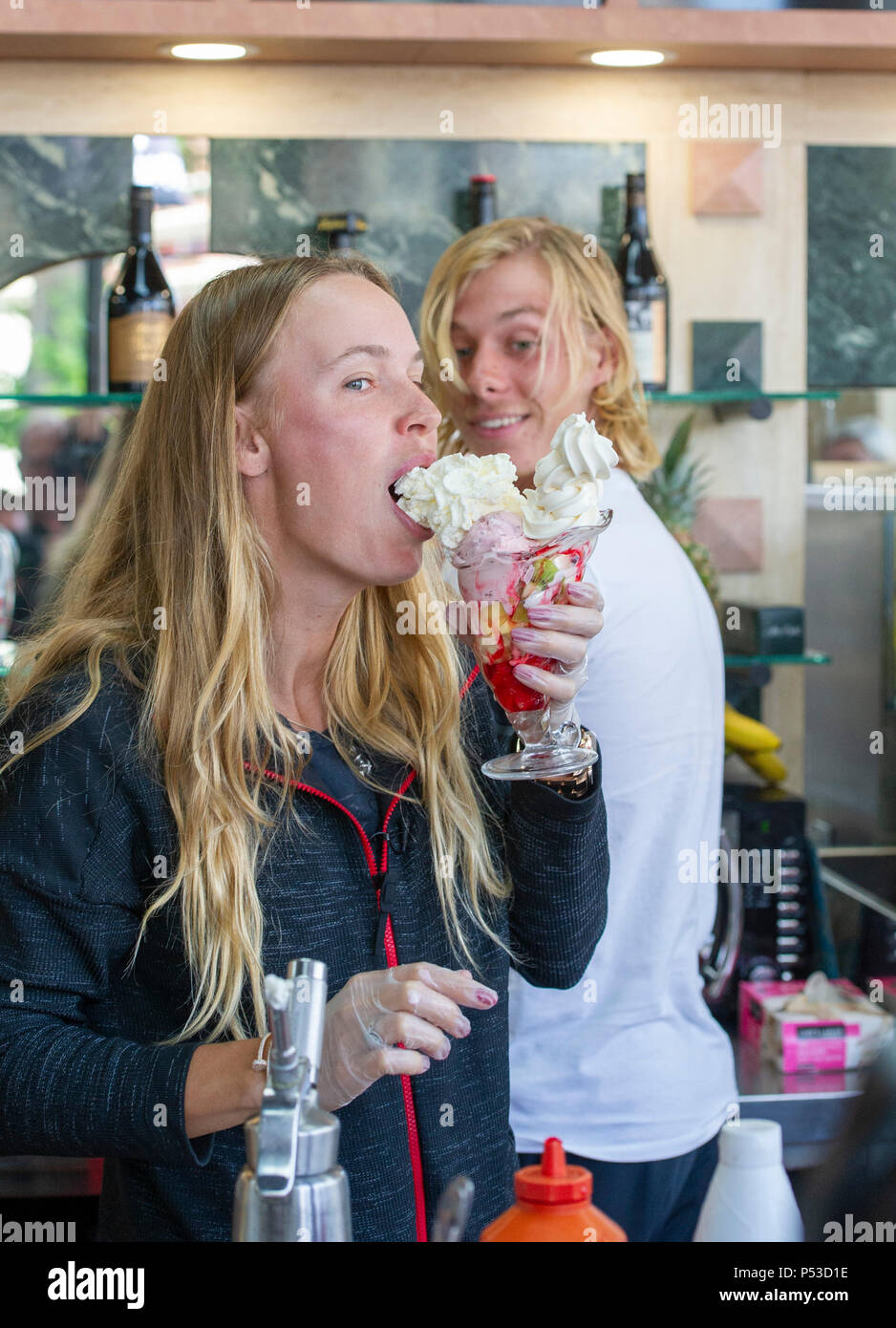 Caroline Wozniacki aus Dänemark von Denis Shapovalov von Kanada beobachtete genießt, und Essen einen Eisbecher in einem lokalen Eisdiele während der Natur Tal internationalen Tennisturnier in Devonshire Park in Eastbourne East Sussex UK. 24. Juni 2018 Stockfoto