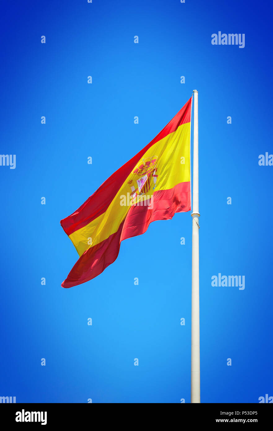 Spanische Flagge schwenkten gegen den klaren blauen Himmel Stockfoto