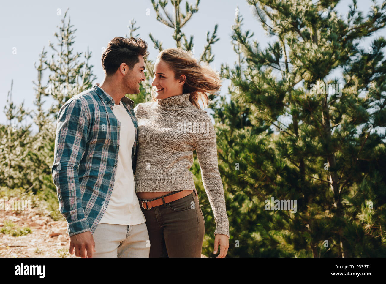 Liebevolle junge Paar an jedem anderen suchen und lächelnd. Mann und Frau stehen im Freien auf Mountain Trail beim Wandern. Stockfoto
