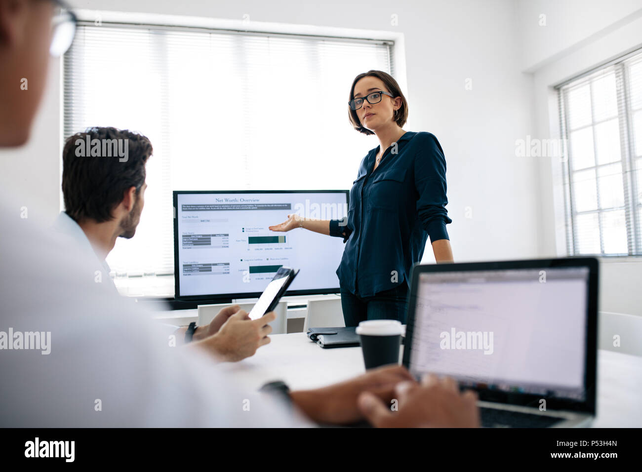 Geschäftsfrau Tragen einer Brille eine Präsentation, die ihre Kollegen im Büro. Büro Kollegen bei Laptops während der Wiedergabe Stockfoto