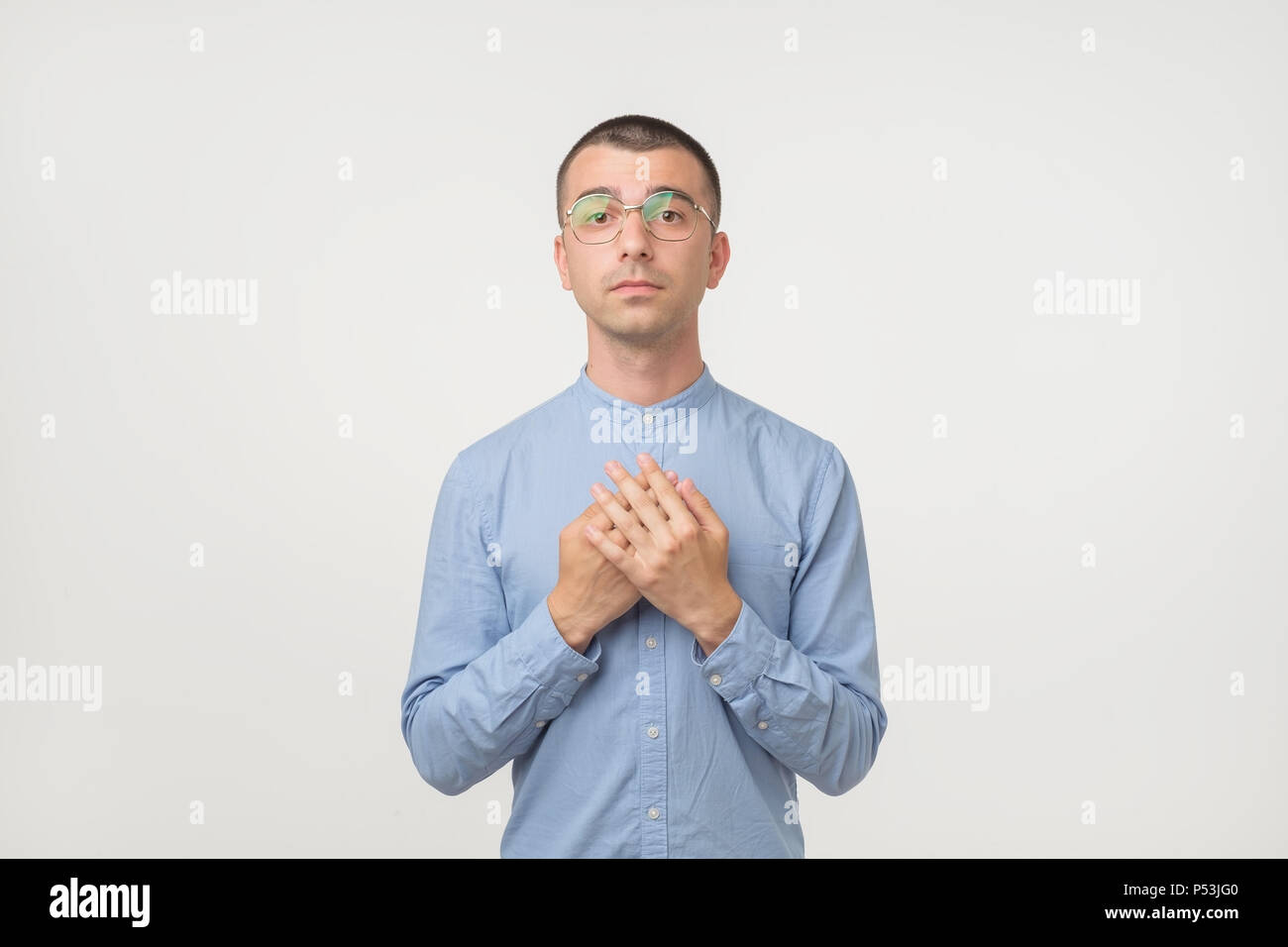 Junge Hispanic Mann in Gläsern und blaues T-Shirt mit einfachen Emotion auf Gesicht, als er um Gnade zu bitten, Stockfoto