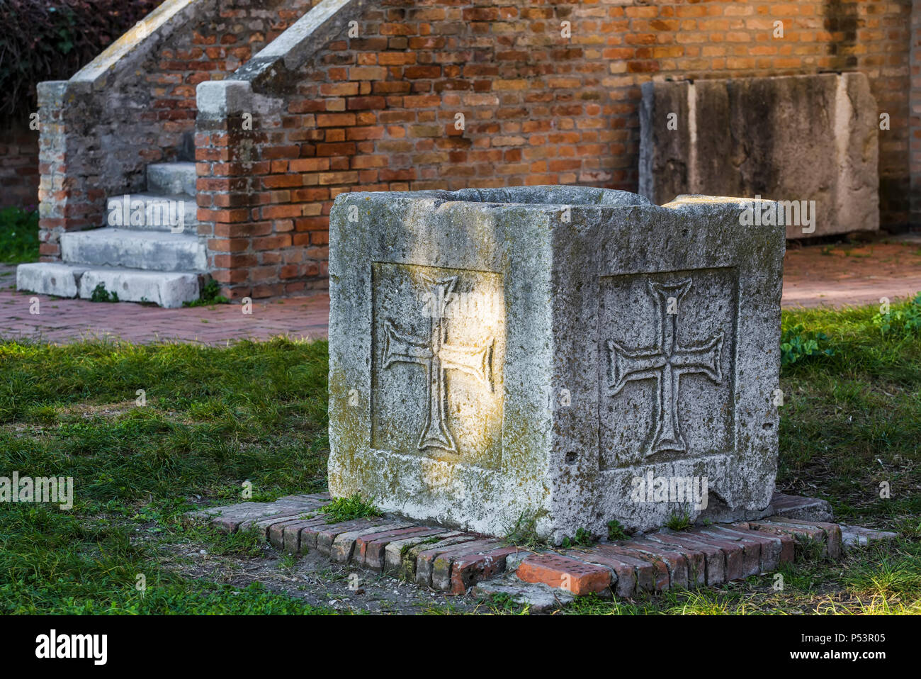Dekorative Vase aus Beton mit religiösen Symbolen, stehend auf einem grünen Rasen Stockfoto