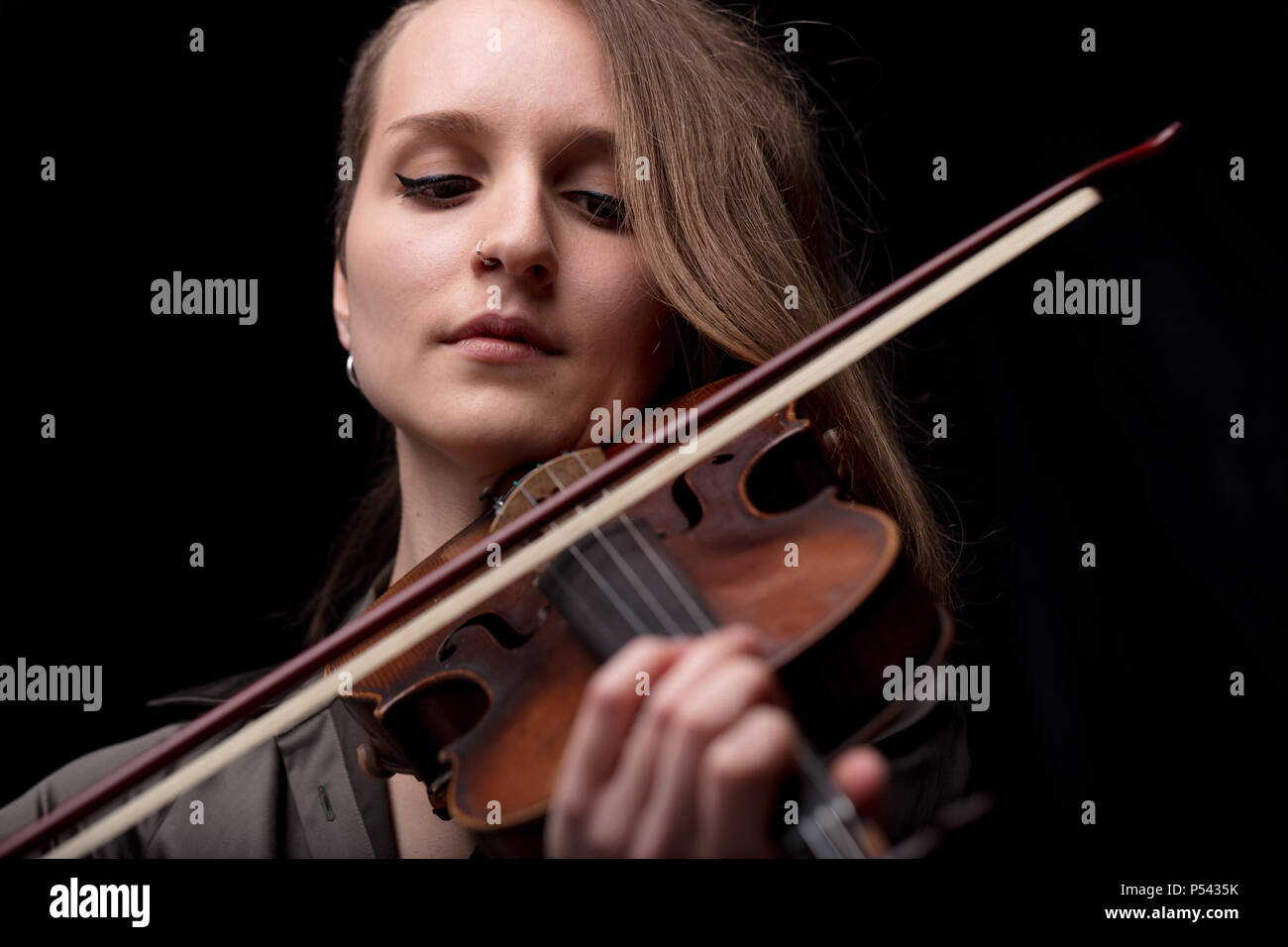 Ernste und konzentrierte Violine player - Porträt einer Frau auf schwarzem Hintergrund spielen Streicher Stockfoto