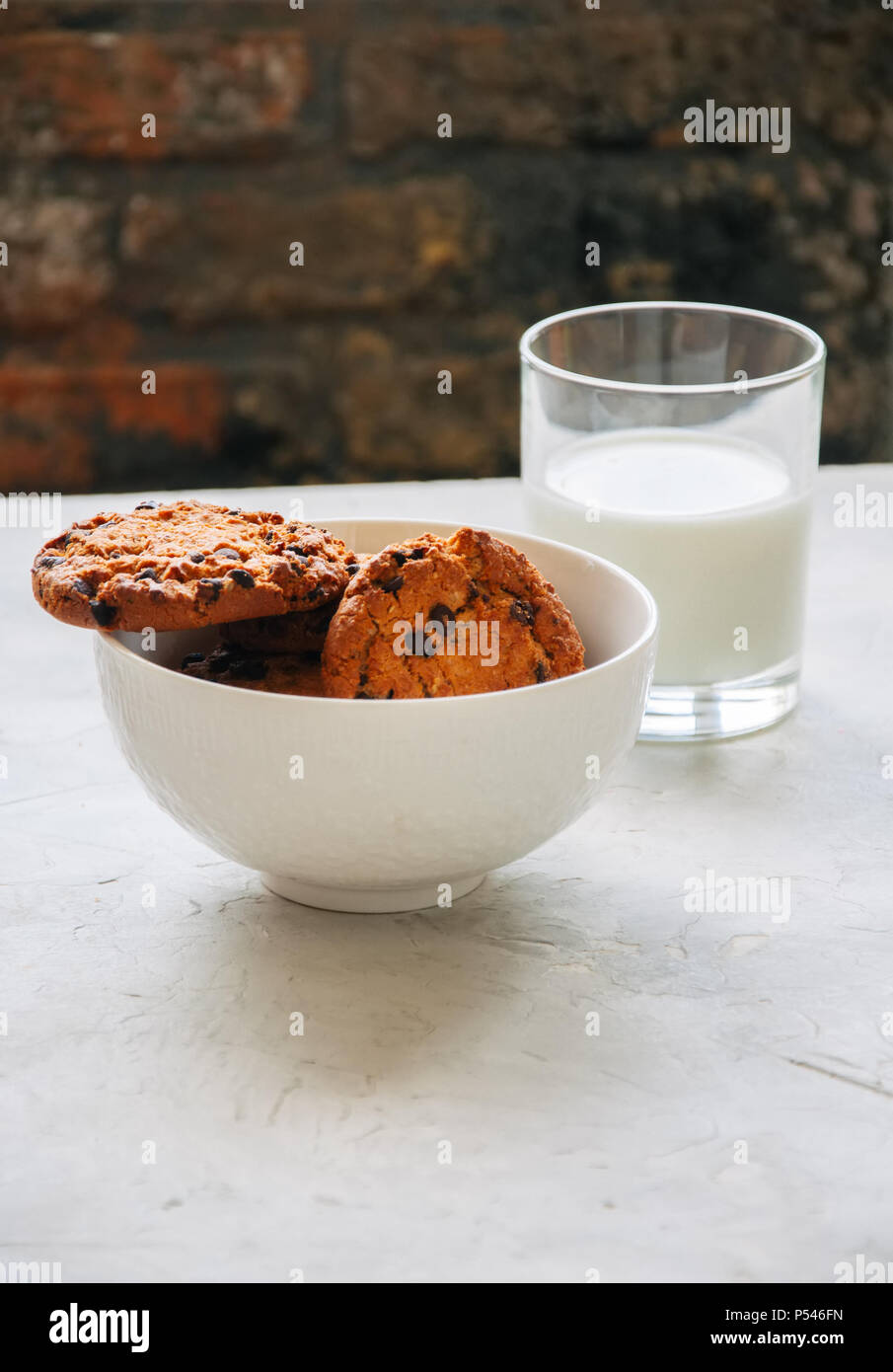 Amerikanische Chocolate Chip Cookies mit Glas Milch auf einen weissen Stein Hintergrund. Top ansehen und kopieren. Stockfoto