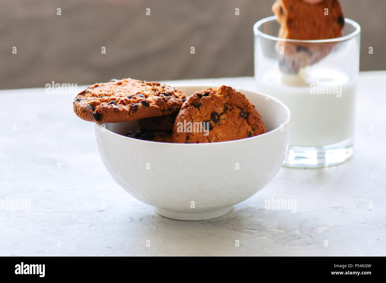 Amerikanische Chocolate Chip Cookies mit Glas Milch auf einen weissen Stein Hintergrund. Top ansehen und kopieren. Stockfoto