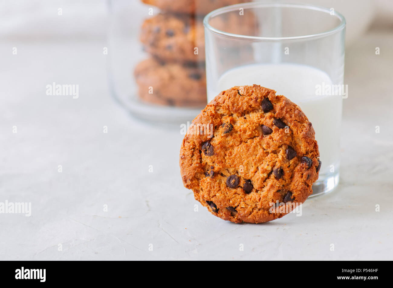 Amerikanische Chocolate Chip Cookies mit Glas Milch auf einen weissen Stein Hintergrund. Top ansehen und kopieren. Stockfoto