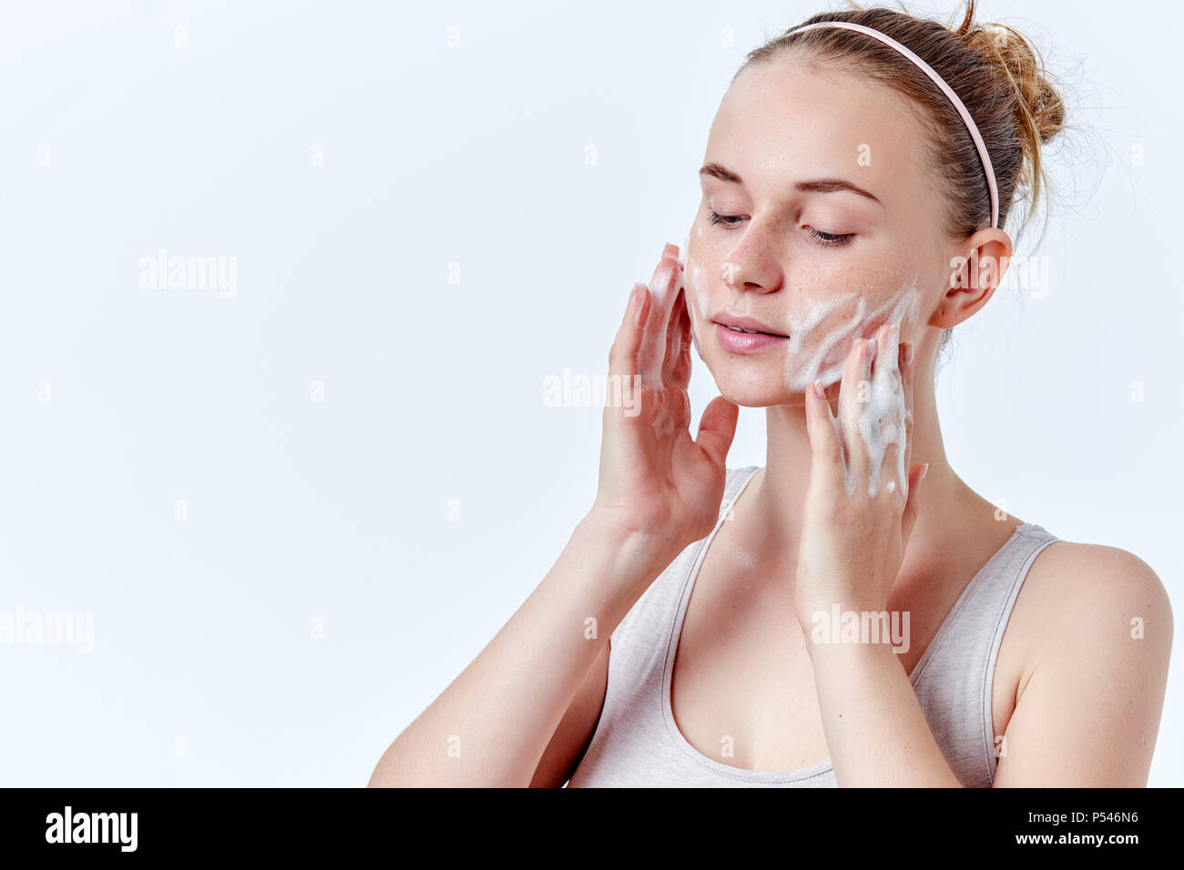 Teenager Hautpflege. Schöne Mädchen im Teenageralter mit Sommersprossen und blaue Augen mit Foaming Cleanser. Gesicht waschen Konzept auf weißem Hintergrund. Stockfoto