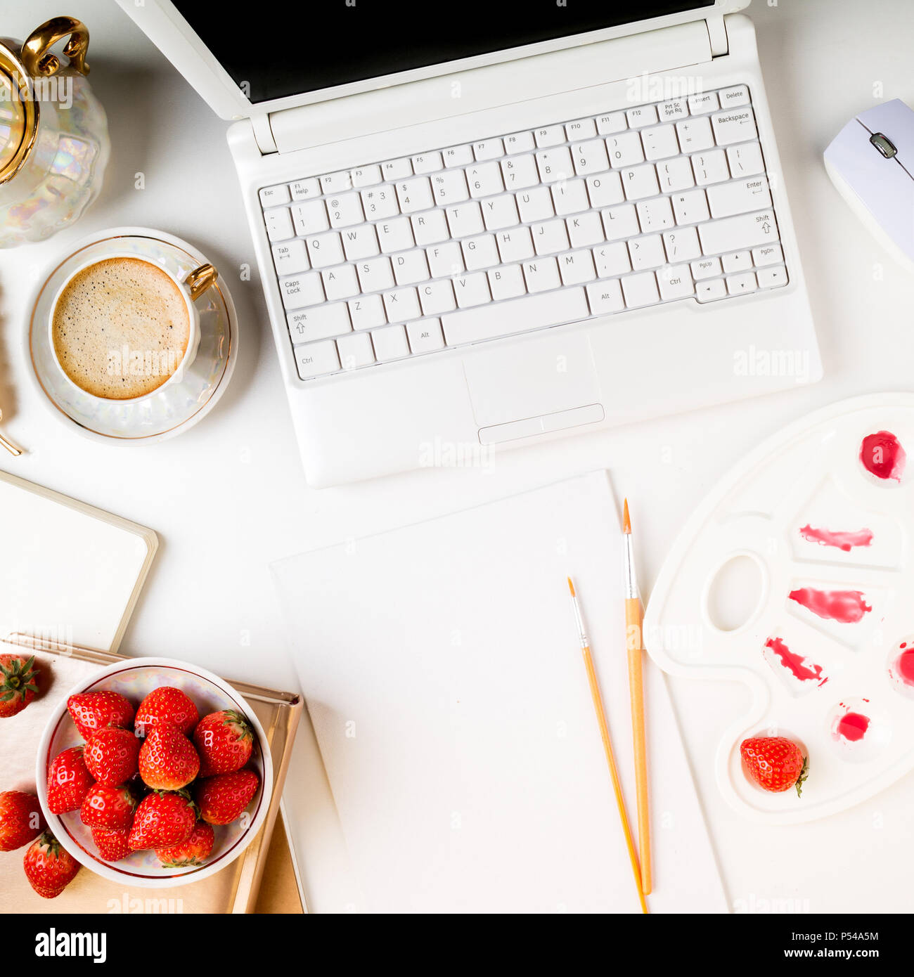 Flach trendy feminine Home Art Arbeitsbereich. Home office Schreibtisch mit Laptop, Notebook, Farben, Pinsel, Leinwand, frische Erdbeeren und Kaffee Tasse auf whi Stockfoto