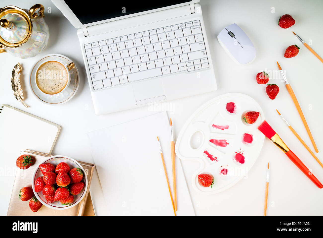 Flach trendy feminine Home Art Arbeitsbereich. Home office Schreibtisch mit Laptop, Notebook, Farben, Pinsel, Leinwand, frische Erdbeeren und Kaffee Tasse auf whi Stockfoto
