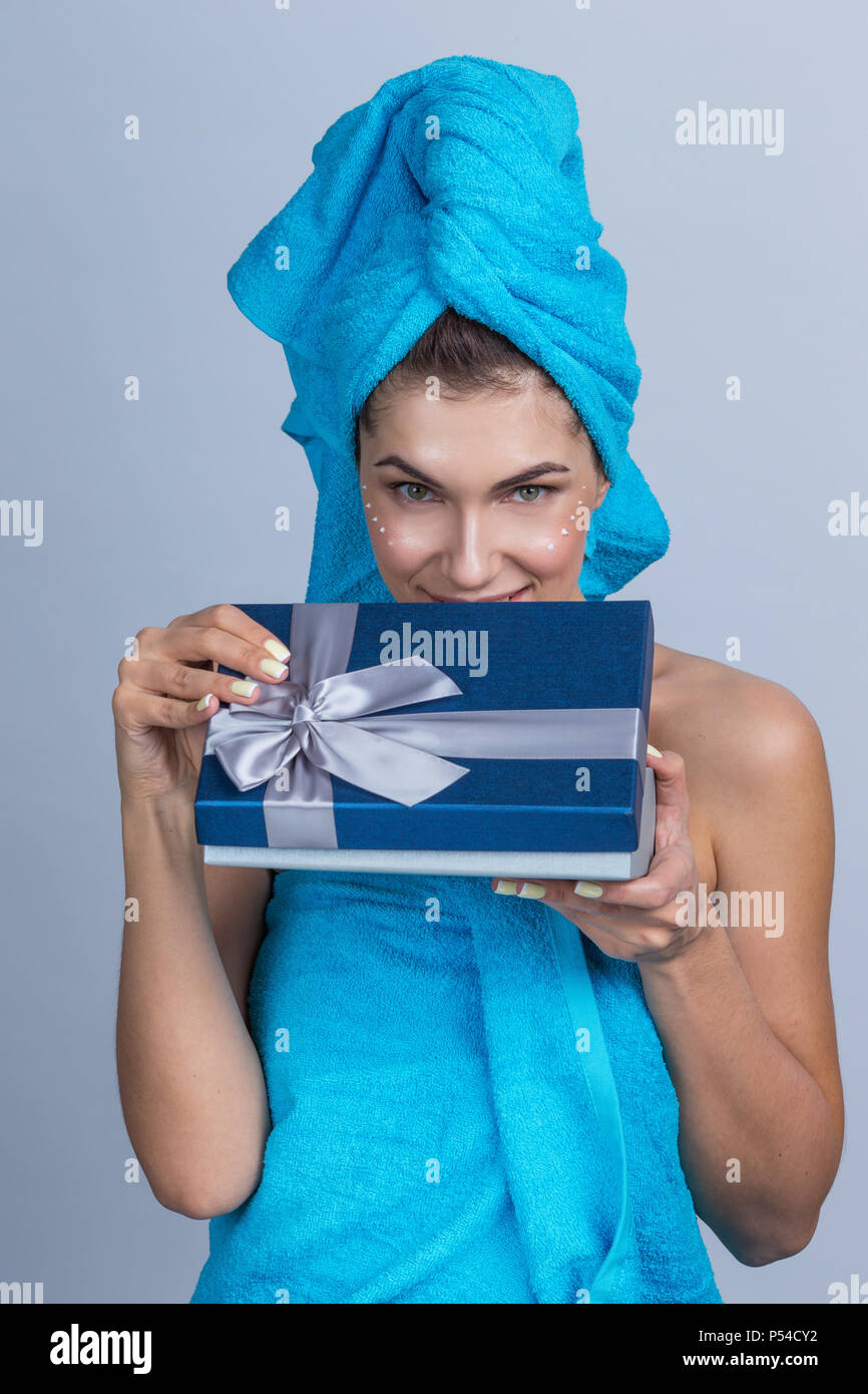 Schöne Frau mit Handtuch auf dem Kopf, die Creme nach Dusche und Holding Geschenkbox Stockfoto