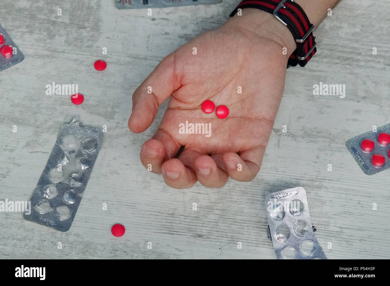 Des Menschen Hand mit leeren Pillen, rote Tabletten in die Hand eines jungen Mannes, Konzept der Selbstmord, Vergiftung von Pillen, Überdosis Drogen. Medikament Stockfoto