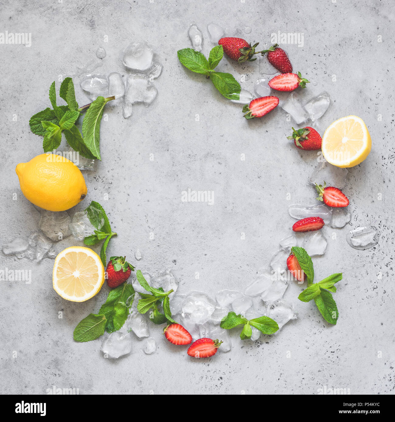 Minze, Eis, Erdbeeren und Zitrone. Erfrischende Sommer Limonade Zutaten wie einen Kranz auf grauem Beton Hintergrund mit Platz für Text kopieren Stockfoto