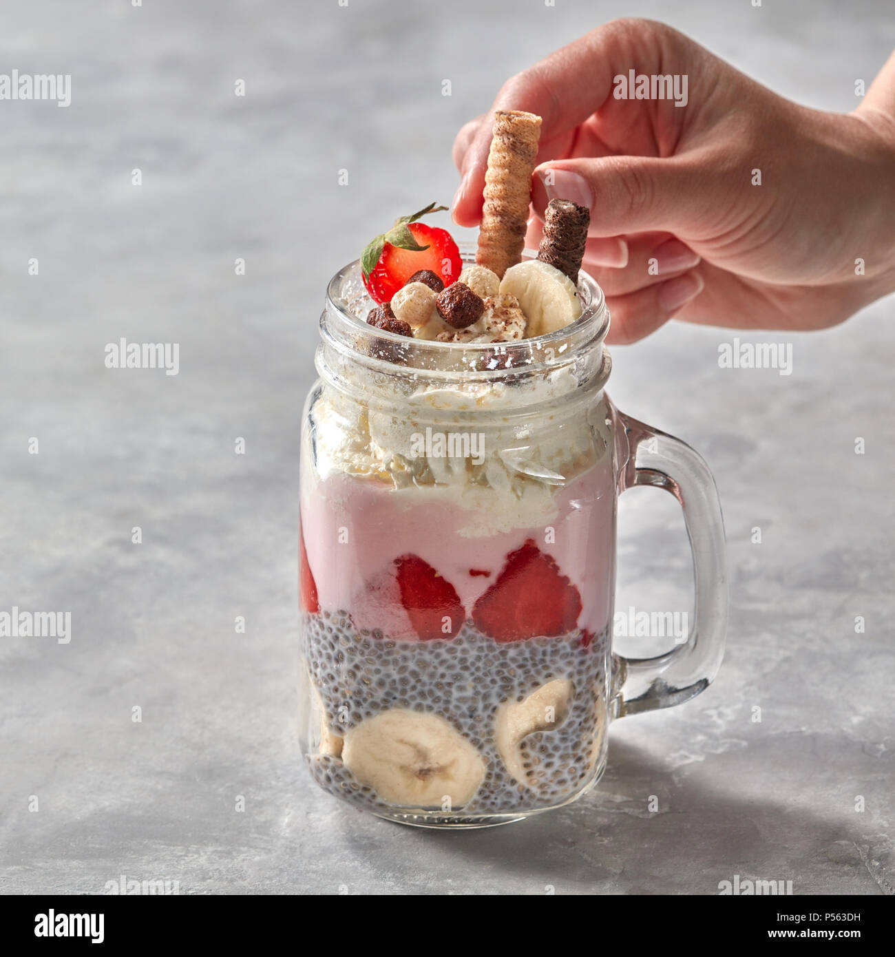 2-in-1-berry und Chia Samen Smoothies im Glas, Mädchen Hand dekorieren Cookies auf grauem Beton Hintergrund. Stockfoto