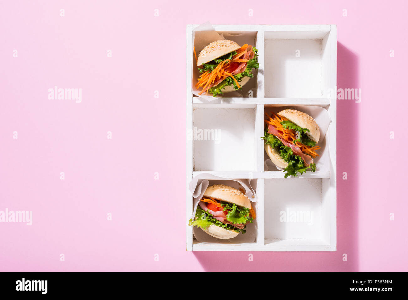 Hausgemachte mini Burger mit Schinken, Tomaten, Möhren, frischem Salat in der alten weißen wooben Box auf rosa Hintergrund serviert. Gesunde junk food Konzept mit Kopie spa Stockfoto
