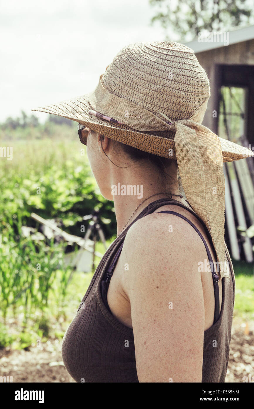 Frau mit Hut mit Blick auf den Garten Stockfoto
