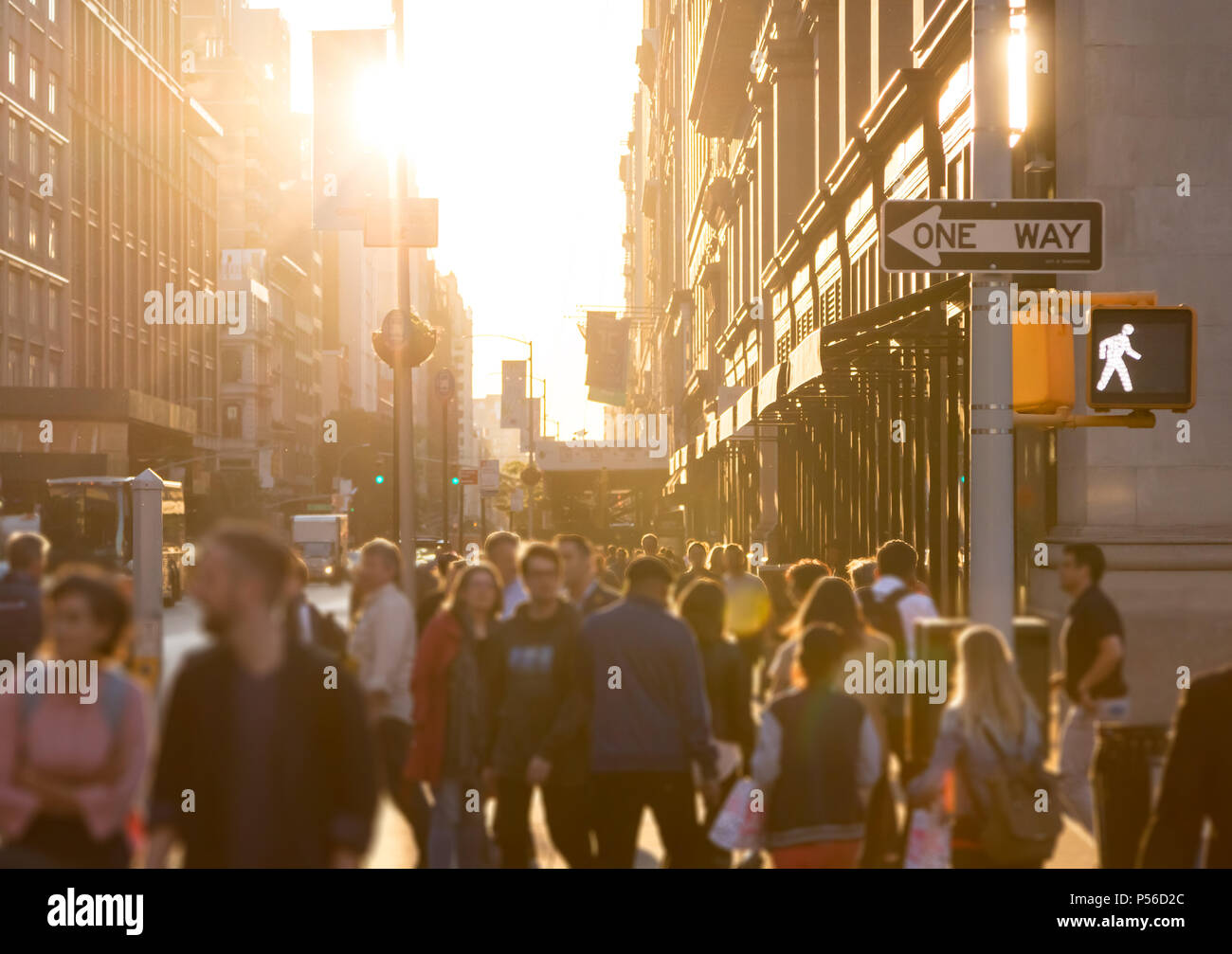 Diverse Masse von anonymen Personen auf einer belebten Straße in Manhattan, New York City mit hellem Sonnenlicht im Hintergrund glänzend Stockfoto