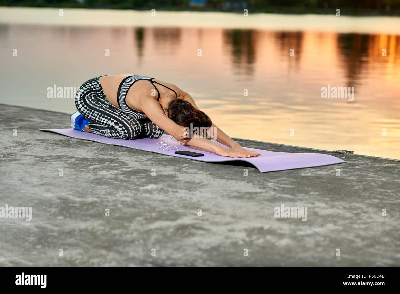 Passende Frau Yoga Posen in der Nähe der Stadt See bei Sonnenuntergang. Im freien Training an der frischen Luft. Modell in Slim , Körper, wunderbare Figur. Die Aufrechterhaltung gesunder Lebensstil. Sport, Yoga, Fitness. Stockfoto